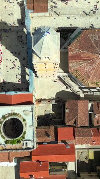 Aerial drone view over historical Zadar town center with cathedral tower and terracotta rooftops during sunny day.