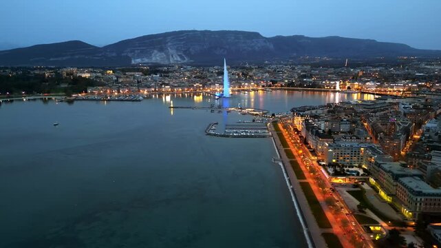 Aerial view of geneva city skyline and lake geneva with famous jet d eau fountain at blue hour.