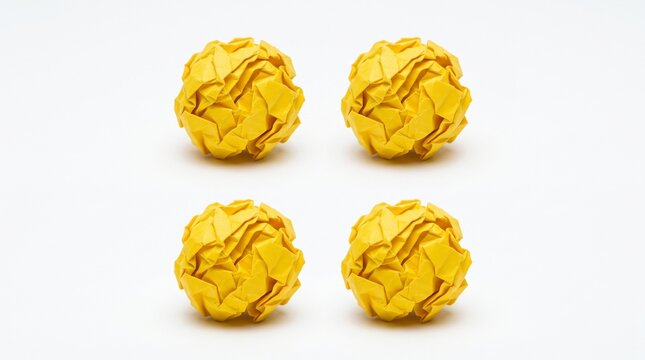 Four crumpled yellow paper balls on plain surface