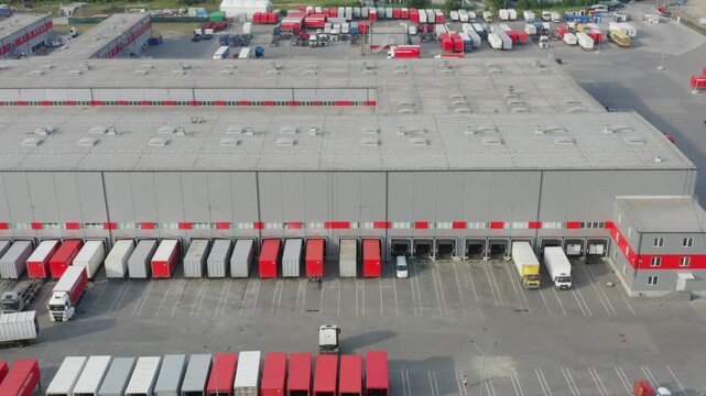 Aerial View of Logistics Warehouse Complex with Trucks Loading at Dock | Semi-Trailer Trucks Standing at Ramps for Loading and Unloading Goods | Drone Shot of Distribution Center Operations