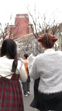 Two Young Women Walking Through Harajuku District in Tokyo Japan