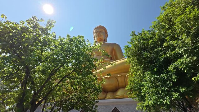 The majestic golden Buddha statue at Wat Paknam Bhasicharoen temple in Bangkok, Thailand, towering above the temple complex in a striking and peaceful setting.
