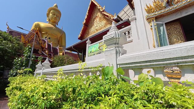 The majestic golden Buddha statue at Wat Paknam Bhasicharoen temple in Bangkok, Thailand, towering above the temple complex in a striking and peaceful setting.
