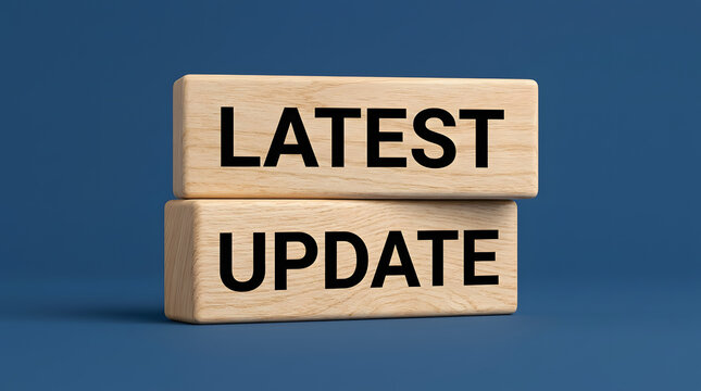 Two light-colored wooden blocks with the words LATEST and UPDATE printed in bold black letters stacked on a solid dark blue background featuring text, message, concept, business and technology
