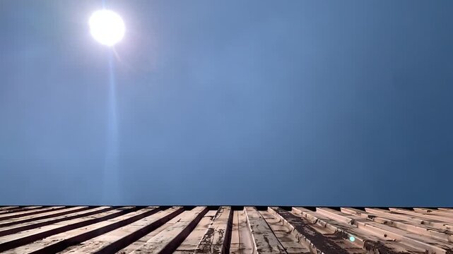 Close-up of a red weathered cargo container with rust and dents with blue sky
