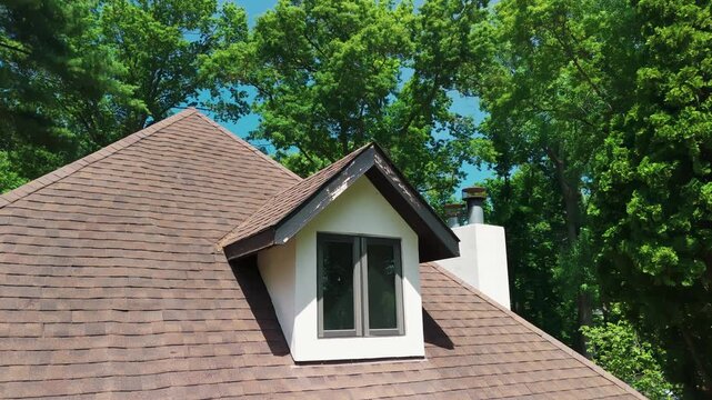 Residential roof gable with weathered wooden fascia and trim showing peeling paint and exterior wear. Home roof detail highlighting the need for maintenance
