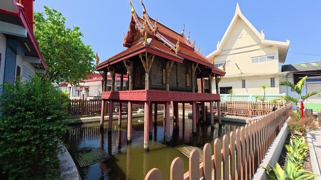 Stunning traditional Thai wooden Sala pavilion standing over water at a historic Bangkok temple, showcasing rich cultural heritage and beautiful oriental architecture. Sala thai near Wat Paknam.