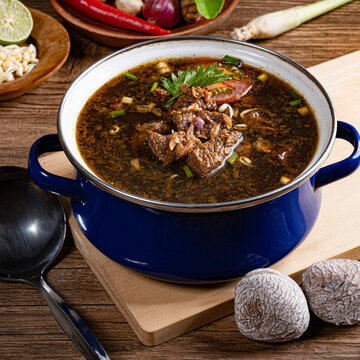 Authentic east javanese rawon beef soup in blue enamel pot with keluak nuts and spices