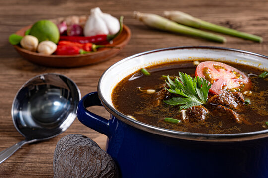 Close up of authentic rawon east javanese dark beef soup with keluak nuts and herbs