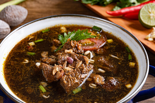 Macro close up of rawon traditional indonesian dark beef soup with fried shallots