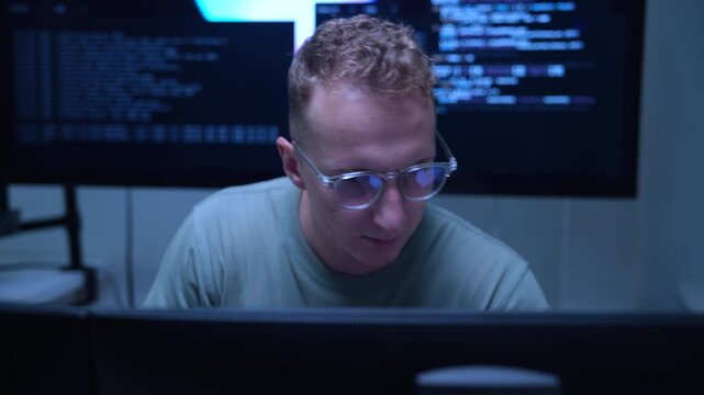 Focused AI developer and technology professional working at computer workstation in modern office, coding software and analyzing data for artificial intelligence project.