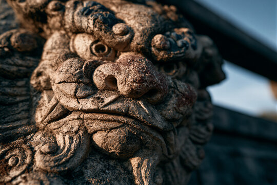 Close-up of weathered ancient stone lion on bridge railing, cinematic golden hour lighting against cool blue sky, shallow depth of field, perfect for cultural heritage and historical documentary use.
