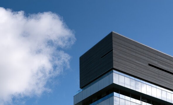 Modern building corner with glass facade against a bright blue sky