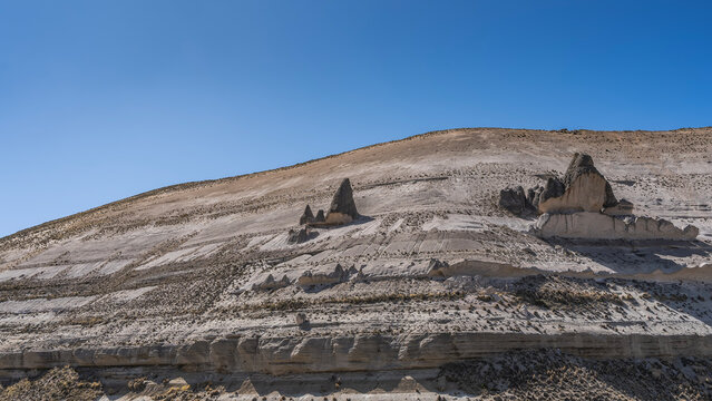 On the vegetation-free mountainside there are bizarre rock formations in the form of smurf houses with sharp conical roofs. The blue sky. Peru. A high-altitude area.
 
