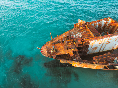 Aerial view of the rusted remains of the Gulf Dove shipwreck resting in clear turquoise waters with visible metal structures and debris in Hulaf, Yemen.