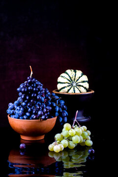 Still life with grapes and a decorative pumpkin on a dark background
