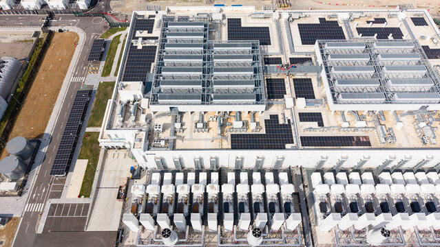 Aerial view of a modern data center facility featuring rooftop solar panels and HVAC units, highlighting advanced digital infrastructure and energy-efficient technology in Melegnano, Lombardy, Italy.