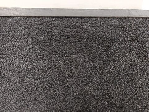 Dinding warna hitam dengan texture batu kecil atau kerikil