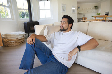 Naklejka premium African American man sitting in living room on wood floor wearing white tee blue jeans wristwatch