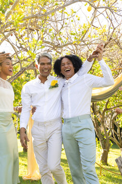 African grooms walking grass aisle under lemon trees in white shirts rose pin phone fabric arch
