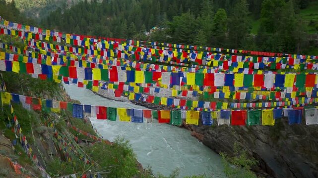 Wide angle shot of colorful Buddhist Tibetan Prayer flags above the flowing Chenab river during the summer season as seen near Triloknath in Lahaul and Spiti district, Himachal Pradesh, India.