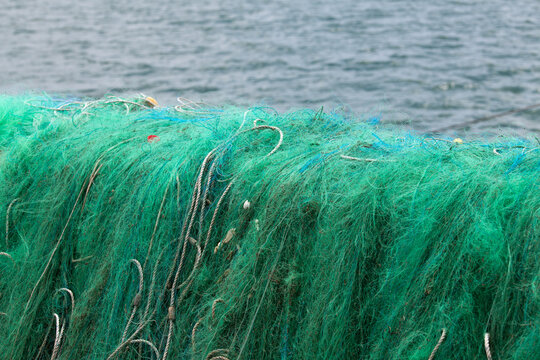 Pile of Vibrant Green Monofilament Fishing Nets by the Sea
