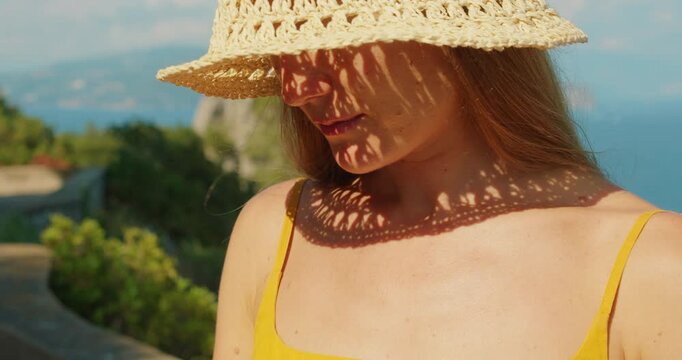 Close view of a young woman in sun hat during a warm golden afternoon walk on Capri