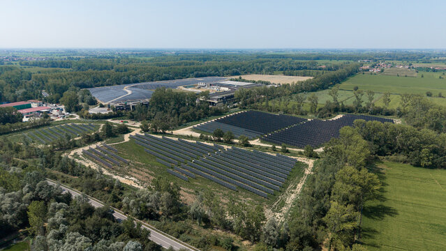 Aerial view of A2A Ambiente Spa - Centro Integrato di Cascina Maggiore facility with solar panel arrays, industrial buildings, and green fields in Cascina Maggiore, Lombardy, Italy.