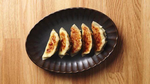 Timelapse shows chef placing gyoza on plate. Modern restaurant plating presents gyoza as elegant Japanese appetizer. Serve gyoza for tasting menu, shared starter, dinner service or Asian buffet.