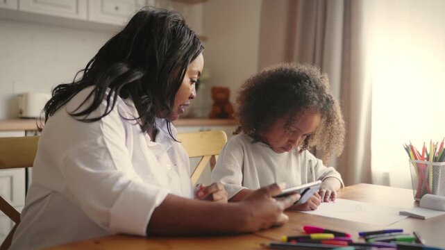Mother and little daughter watching video in internet how draw, home education. Tutor practicing with preschooler, homeschooling and modern technology, use mobile gadgets for studying and knowledge