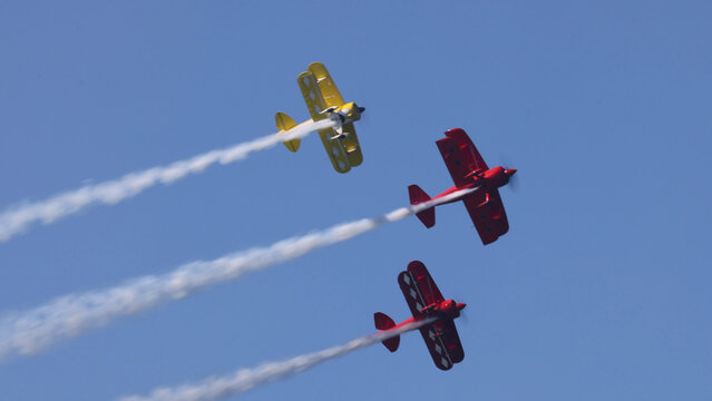 Three Aerobatic Biplanes Flying in Formation with White Smoke Trails