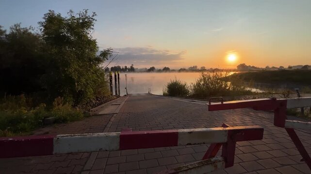 Closed Access Barrier at Empty River Ferry Landing with Morning Mist and Sunrise
