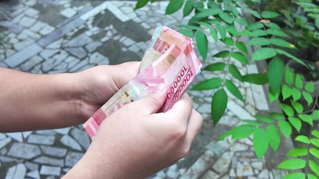 people try to counting money for payment. people holding cash money rupiah. saving money.