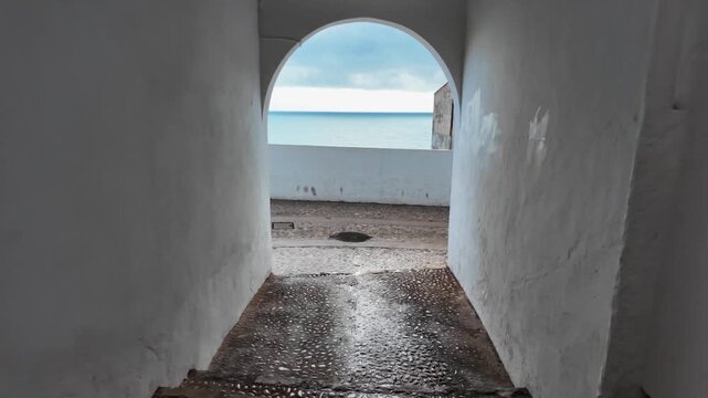 Walking through arched stone gate in old town walls, Altea, Spain