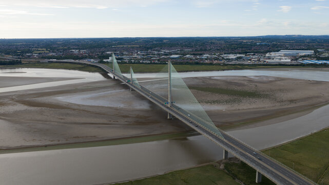 Aerial view of the Mersey Gateway Bridge spanning the River Mersey with mudflats at low tide and the town of Runcorn in the background, Runcorn, United Kingdom.