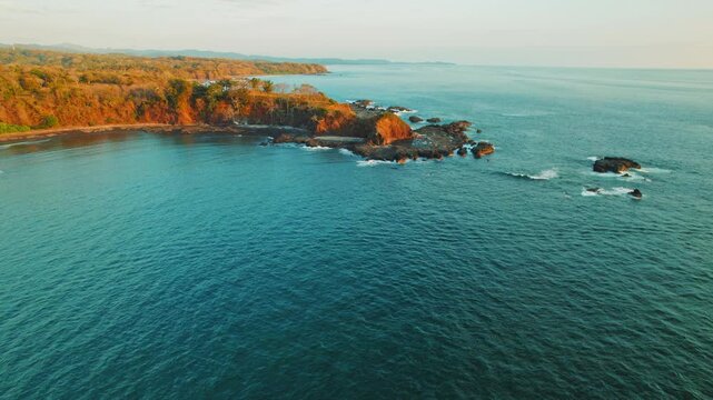 Scenic view of rocky coastline and calm ocean waters of Costa Rica at sunset