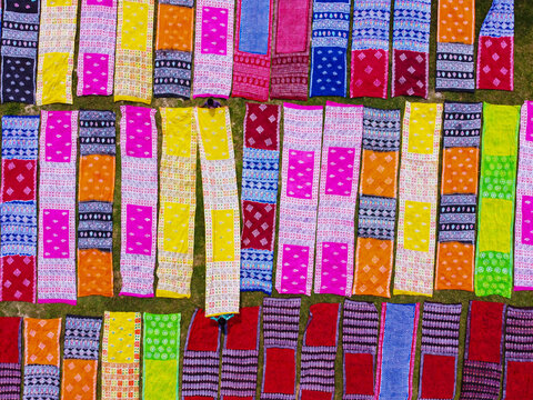 Aerial view of colorful sarees laid out to dry in long rows on the ground, showcasing vibrant patterns and textile production in Narayanganj, Dhaka, Bangladesh.