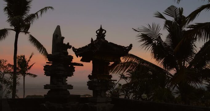 Balinese temple stone shrines standing against tropical sunset sky in Nusa Penida Bali