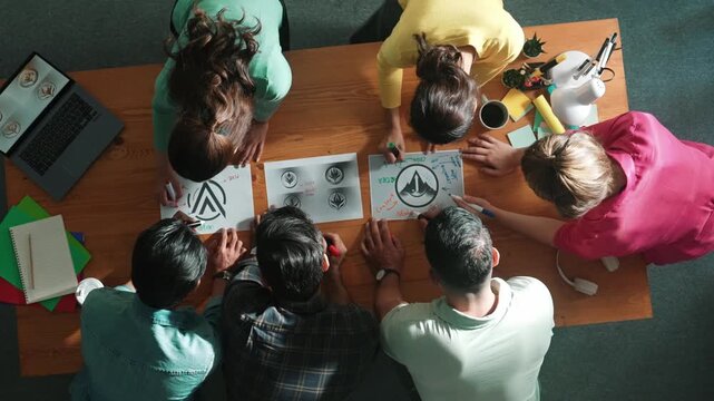 Top view of smart business team put graphic logo on meeting table and start to design while explain idea. Aerial view of project manager show and present plan while talk about concept art. Symposium.