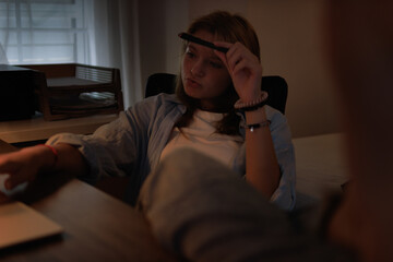Fototapeta premium Teenager student studying at home office late at night, thinking deeply while learning, focused on academic work, back to school education concept