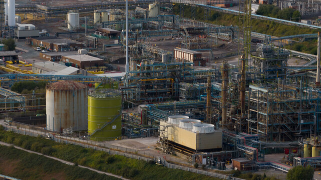 Aerial view of INEOS Electrochemical Solutions industrial chemical plant featuring large storage tanks, cooling towers, and complex pipe networks in Runcorn, England, United Kingdom.