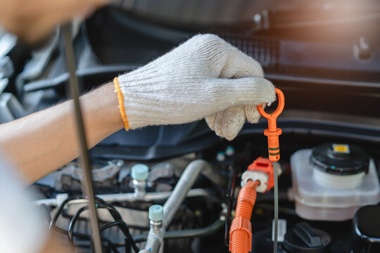 Auto technician performing routine maintenance check on a hybrid car engine.
