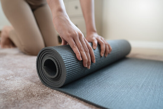 Woman hands rolling black yoga mat after workout on carpet floor at home cozy fitness sport activity concept close up side view texture details healthy lifestyle wellness meditation training indoor
