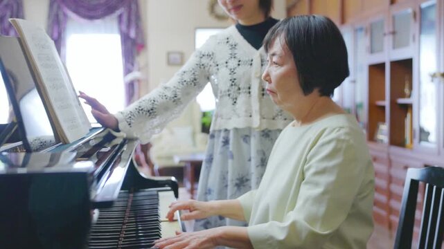 ピアノを演奏するシニア女性と楽譜を確認する大人の女性