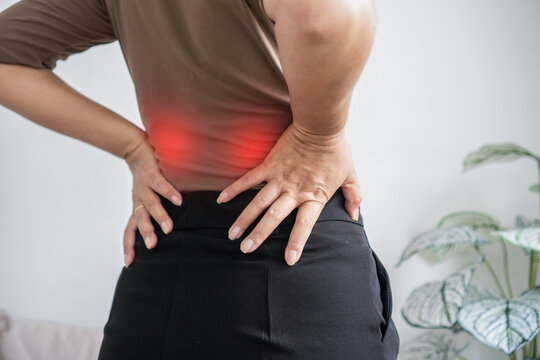 woman touching her lower back suffering from severe lumbar pain, muscle strain, and spine inflammation. Female worker feeling backache and office syndrome pain