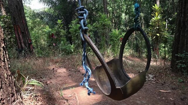 A rustic tire swing hanging from a tree in a lush green forest. perfect for concepts of childhood nostalgia, relaxation, freedom, and peaceful leisure.