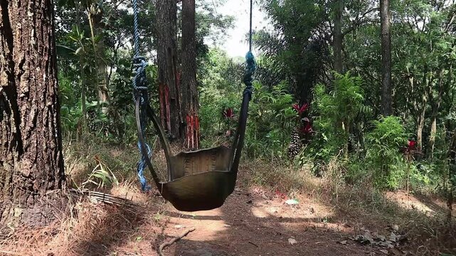 A rustic handmade tire swing hanging from a tall tree in a lush forest. perfect for concepts of childhood nostalgia, relaxation, freedom, and peaceful leisure.