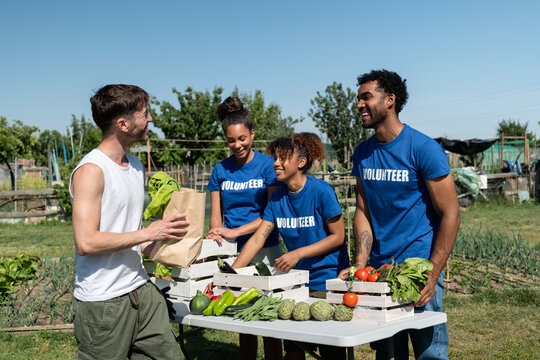 Group of happy volunteers distributing fresh produce from a community garden