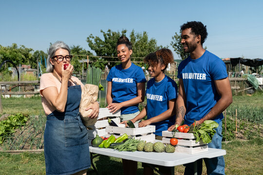 Community volunteers and an older woman enjoying freshly harvested vegetables and fruit