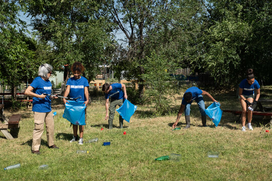 Group of volunteers cleaning up litter in a park, contributing to environmental protection
